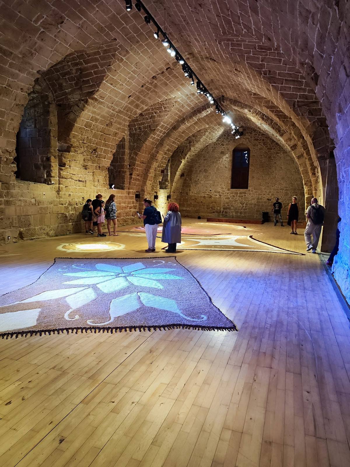 Eutopia installation by Katina Kosta at Kastelliotissa Hall, showing the vaulted stone space and textile works arranged across the floor
